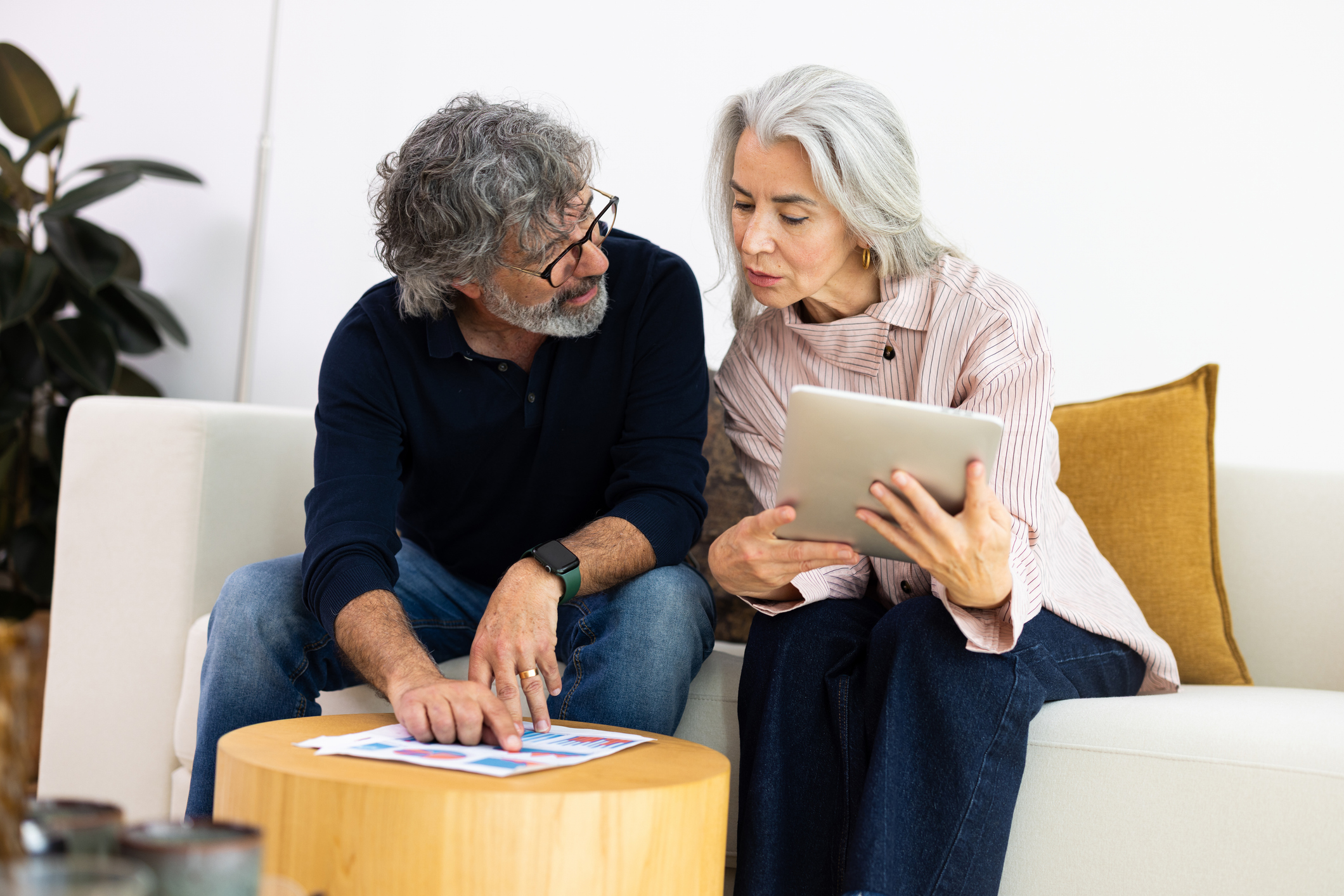 Mature couple discussing finance using digital tablet and paperwork